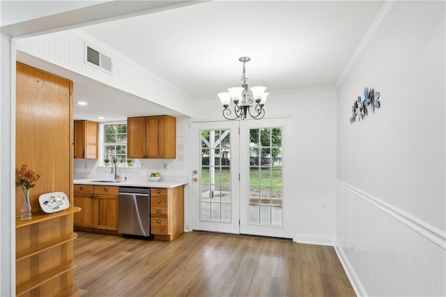 kitchen featuring stainless steel dishwasher, ornamental molding, decorative light fixtures, and sink