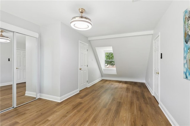 interior space featuring hardwood / wood-style floors, vaulted ceiling, and a closet