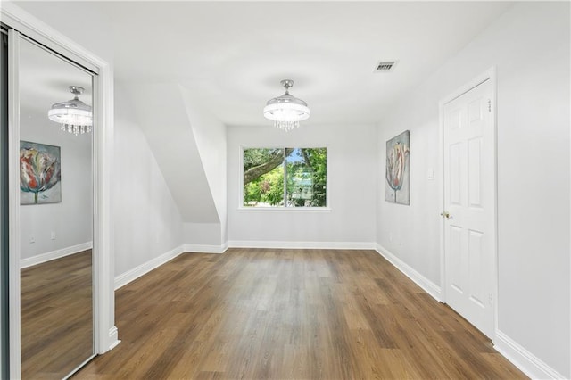 unfurnished room featuring a notable chandelier and dark hardwood / wood-style flooring