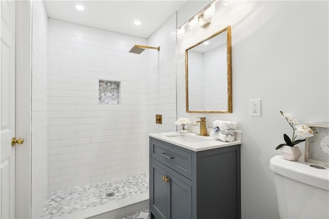 bathroom featuring tiled shower, vanity, and toilet