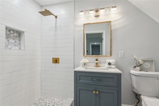 bathroom featuring vanity, tiled shower, and toilet