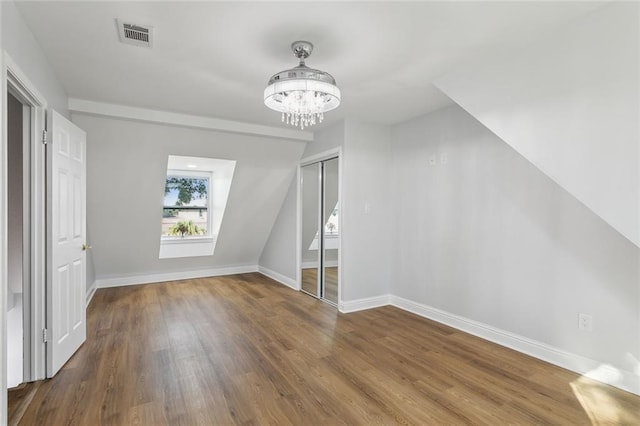 bonus room with hardwood / wood-style flooring and a chandelier