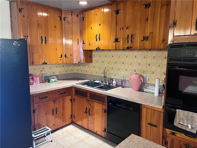 kitchen featuring tasteful backsplash, light tile patterned floors, sink, and black appliances