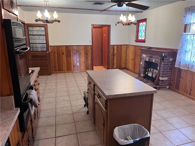 kitchen featuring hanging light fixtures, a kitchen island, light tile patterned floors, and wood walls