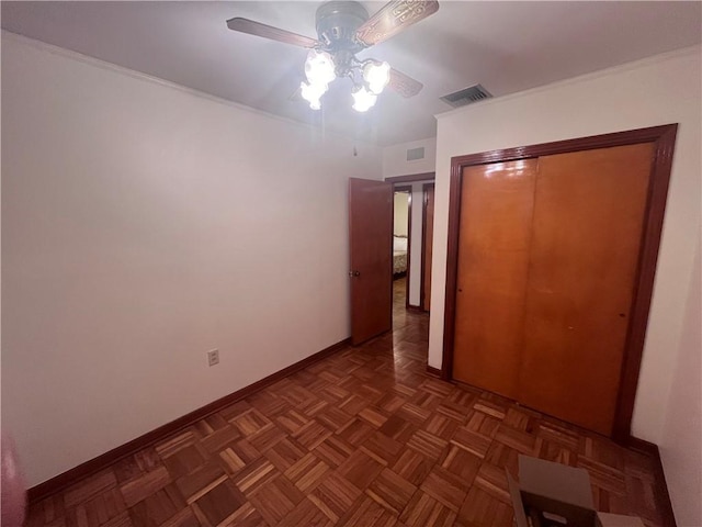 unfurnished bedroom with ceiling fan, dark parquet flooring, and a closet