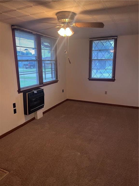 carpeted spare room featuring heating unit and ceiling fan