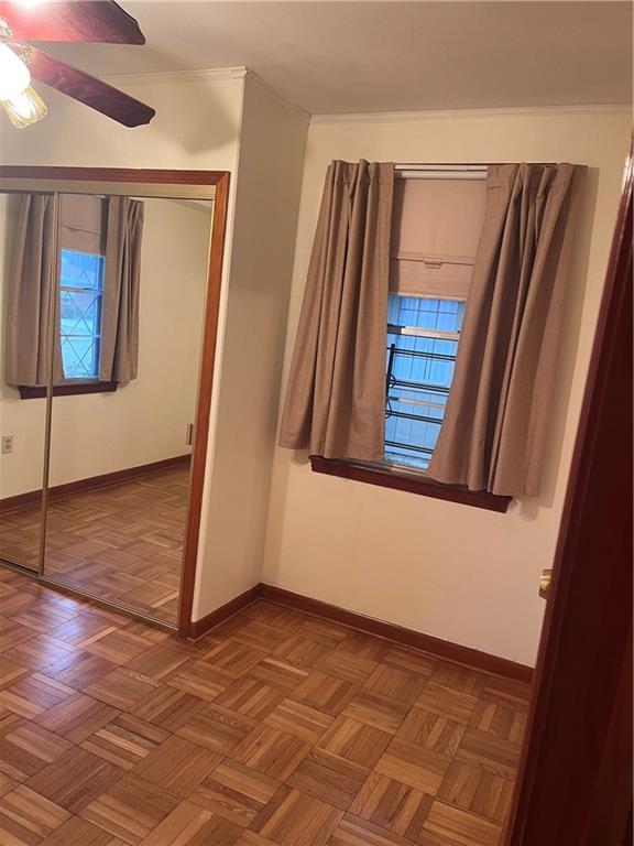 unfurnished bedroom featuring ceiling fan, crown molding, and dark parquet floors