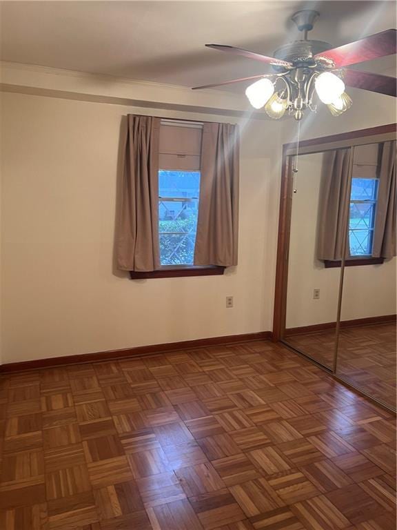 unfurnished bedroom with dark parquet flooring, a closet, and ceiling fan