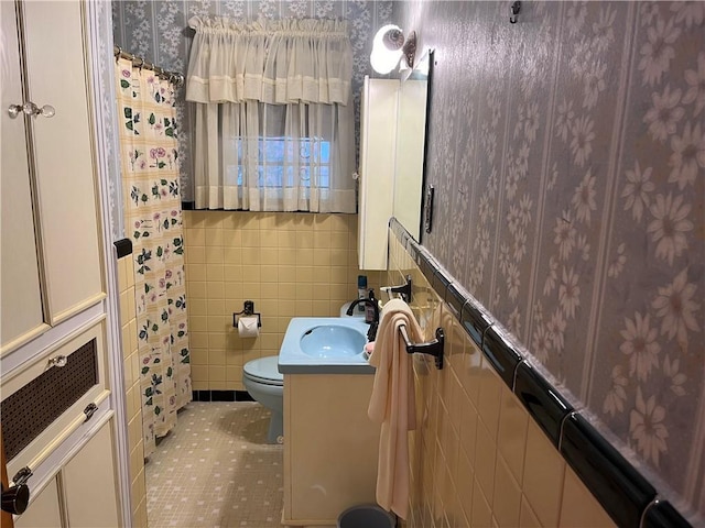 bathroom with tile patterned floors, vanity, toilet, and tile walls