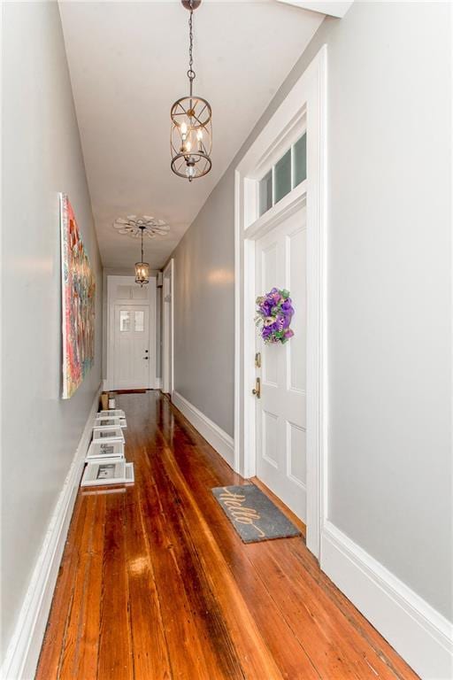 entryway featuring dark wood-type flooring and an inviting chandelier