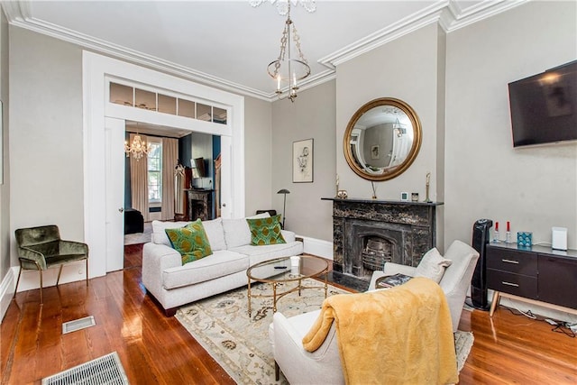 living room featuring ornamental molding, a premium fireplace, wood-type flooring, and a notable chandelier