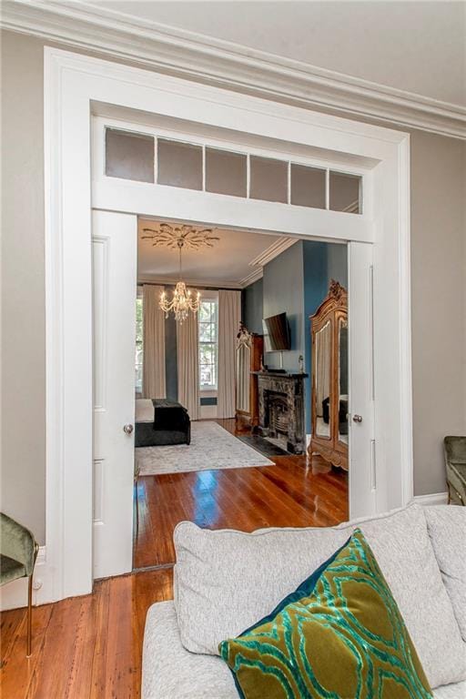 living room with an inviting chandelier, crown molding, and wood-type flooring