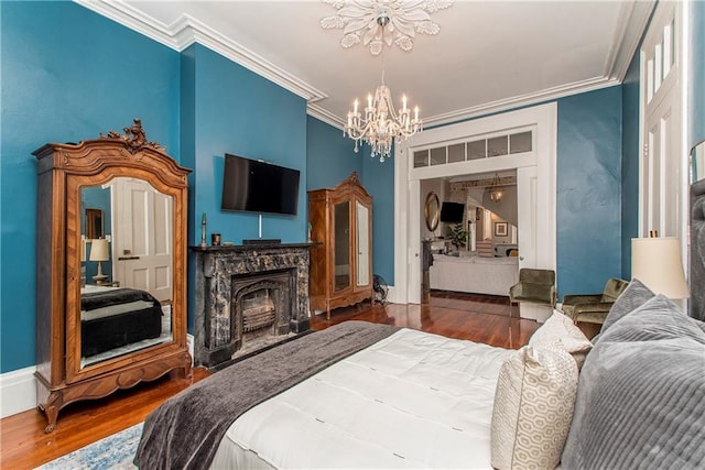 bedroom featuring crown molding, dark wood-type flooring, a high end fireplace, and a chandelier