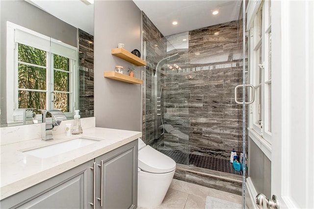 bathroom featuring a shower with door, vanity, tile patterned flooring, and toilet