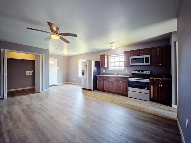 kitchen with stainless steel appliances, ceiling fan, sink, and light hardwood / wood-style floors