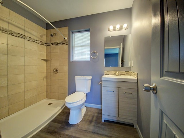 bathroom with vanity, wood-type flooring, toilet, and tiled shower