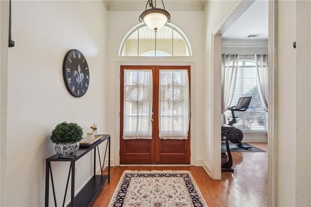 entrance foyer with hardwood / wood-style flooring, ornamental molding, and french doors