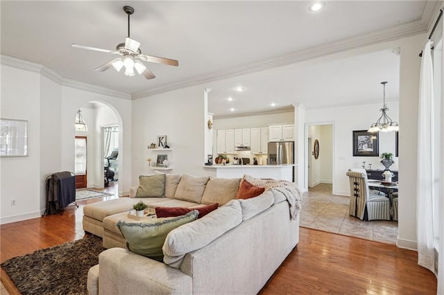 living room with ornamental molding, light hardwood / wood-style floors, and ceiling fan