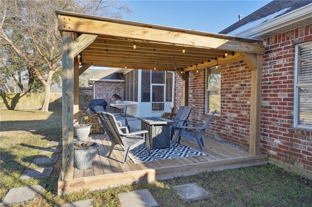 view of patio / terrace with a wooden deck, a sunroom, and an outdoor fire pit