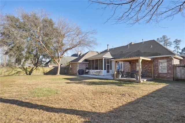 back of property with a lawn, a sunroom, and a patio