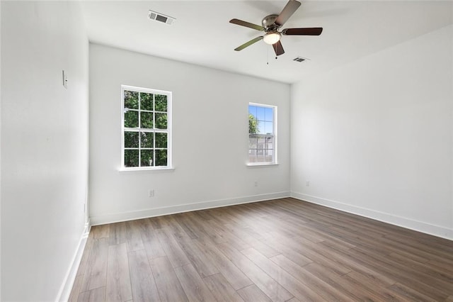 empty room with light wood-style floors, visible vents, and baseboards