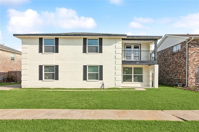 rear view of house with a yard, brick siding, and a balcony