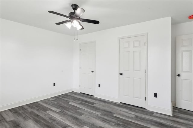 unfurnished bedroom with dark wood-type flooring, a ceiling fan, and baseboards