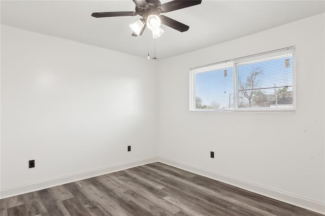 empty room featuring dark wood-type flooring, a ceiling fan, and baseboards