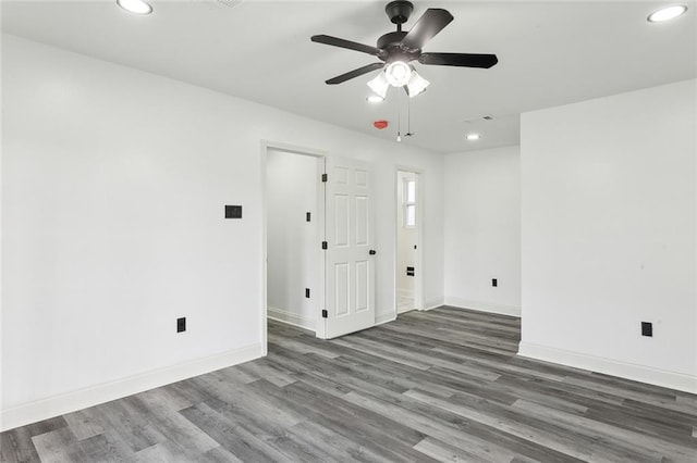 spare room with recessed lighting, wood finished floors, a ceiling fan, and baseboards