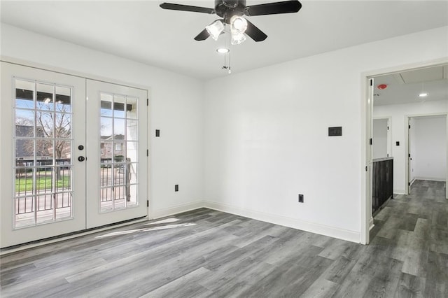 spare room with attic access, french doors, plenty of natural light, and wood finished floors