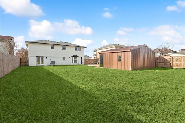 rear view of house featuring a fenced backyard, a lawn, an outdoor structure, and central AC unit