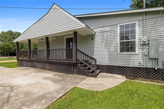 entrance to property with a porch and a yard