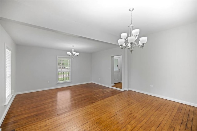 spare room with wood-type flooring and a chandelier