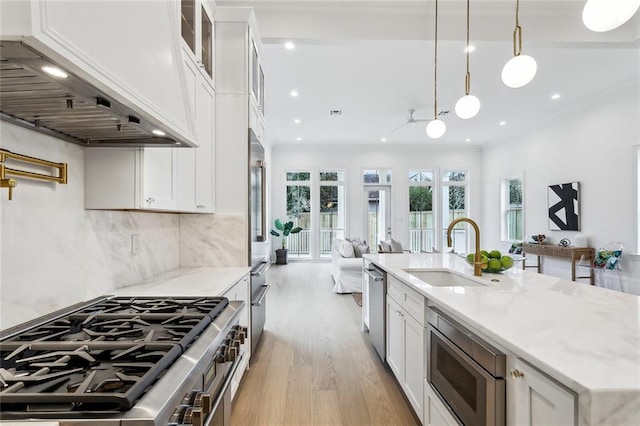 kitchen featuring sink, white cabinetry, stainless steel appliances, custom range hood, and decorative light fixtures