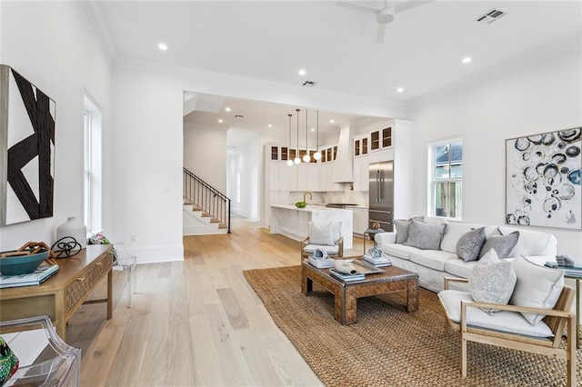 living room featuring sink, light hardwood / wood-style flooring, ornamental molding, and ceiling fan