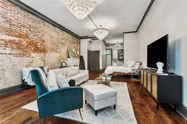 living room featuring dark hardwood / wood-style flooring, brick wall, ornamental molding, and an inviting chandelier