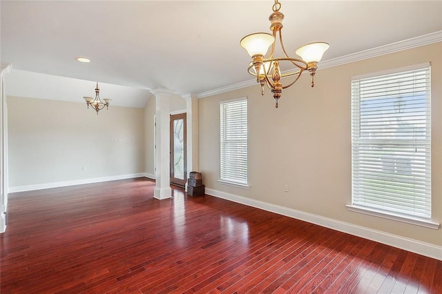 empty room featuring wood finished floors, baseboards, ornate columns, and a chandelier