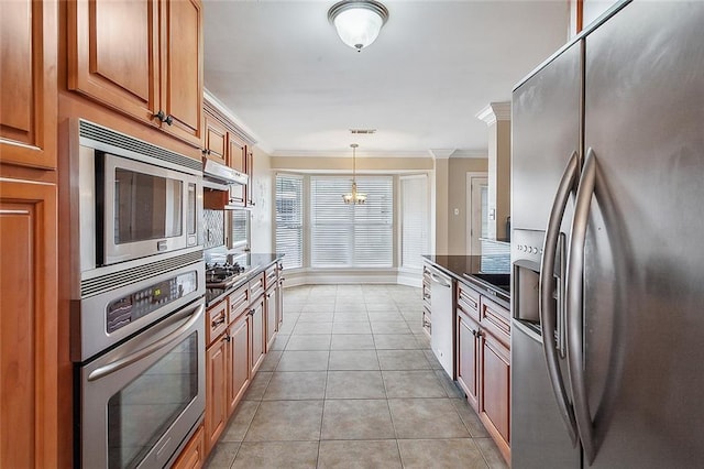 kitchen with brown cabinets, ornamental molding, decorative light fixtures, appliances with stainless steel finishes, and light tile patterned floors