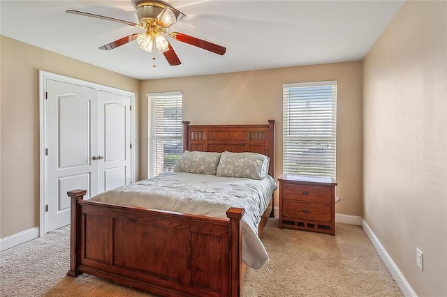 bedroom with light carpet, ceiling fan, a closet, and baseboards