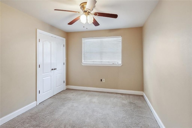 carpeted empty room with a ceiling fan and baseboards