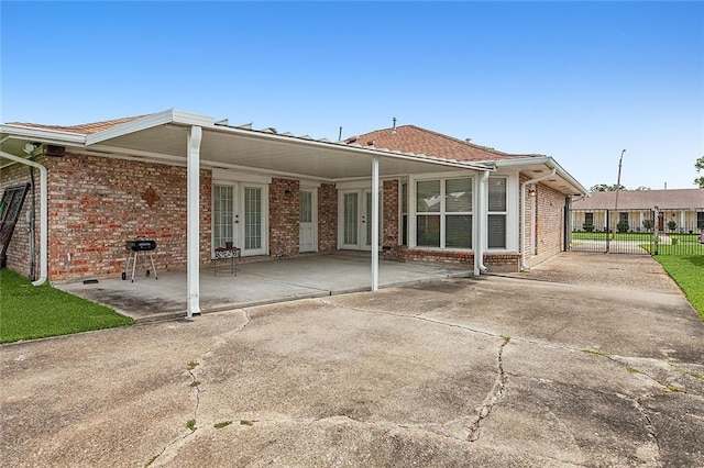 back of property with a patio area, fence, french doors, and brick siding