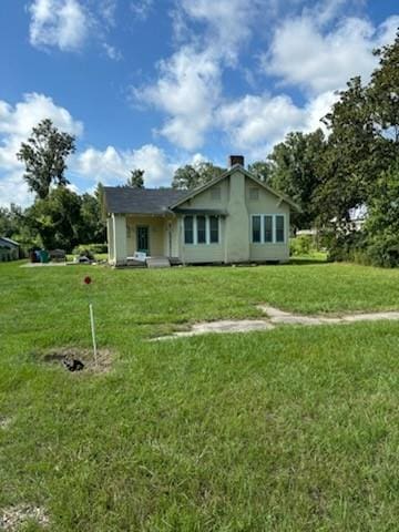 rear view of property featuring a lawn