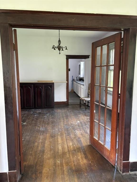 unfurnished dining area featuring a notable chandelier and dark wood-type flooring