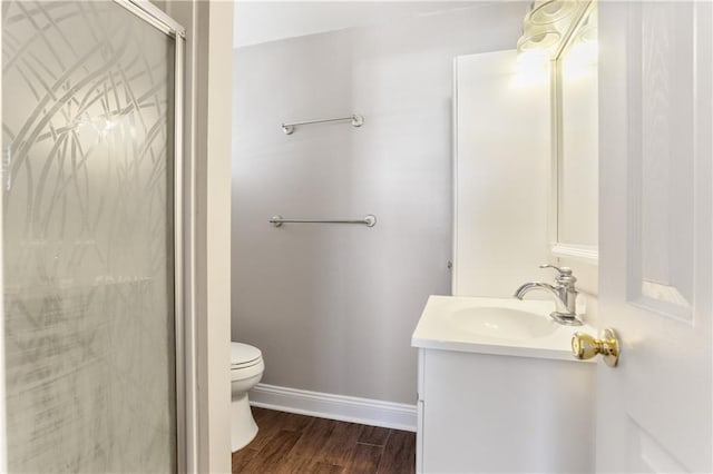 bathroom featuring wood-type flooring, a shower with shower door, vanity, and toilet