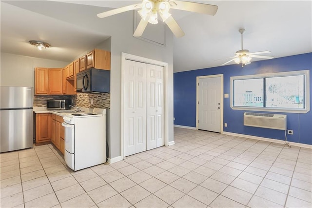 kitchen featuring vaulted ceiling, appliances with stainless steel finishes, light tile patterned flooring, an AC wall unit, and decorative backsplash