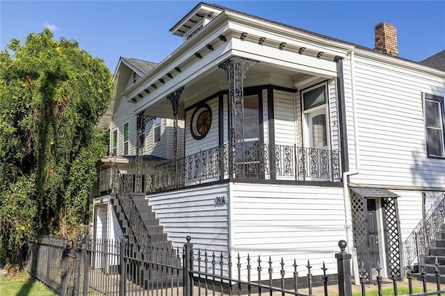 exterior space featuring a fenced front yard, a porch, stairs, a chimney, and a garage