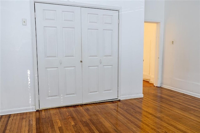 unfurnished bedroom featuring a closet, baseboards, and hardwood / wood-style flooring