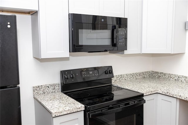 kitchen featuring black appliances, white cabinets, and light stone counters