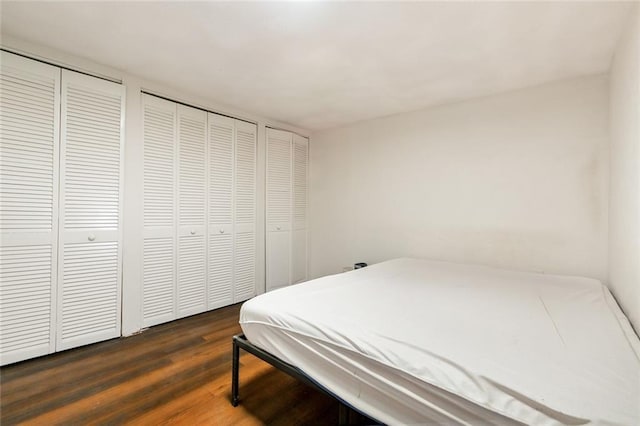 bedroom with two closets and wood finished floors