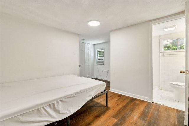 bedroom featuring baseboards, dark wood-type flooring, and ensuite bath